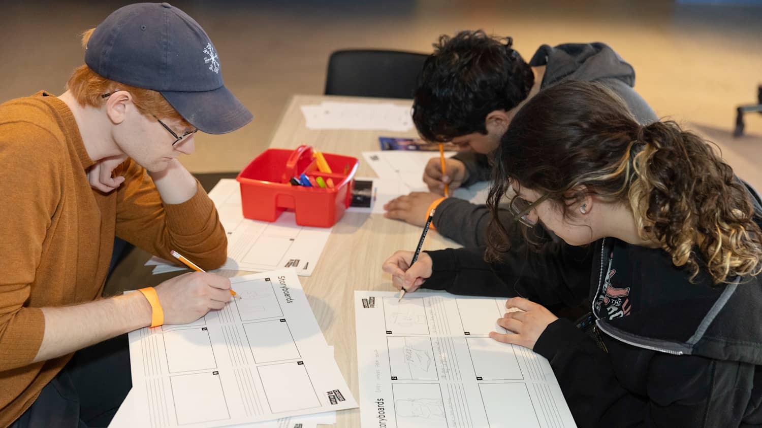 Three teenager drawing storyboards at an art table