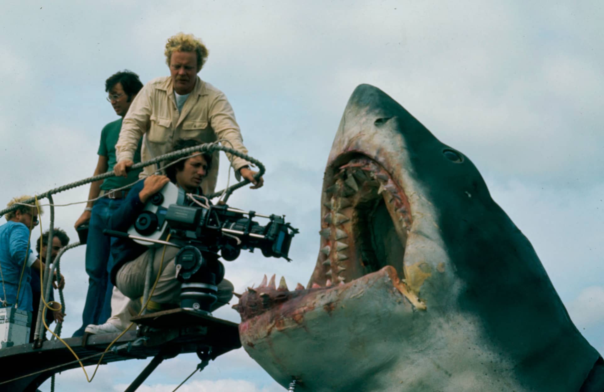 Director Steven Spielberg, kneeling with camera, during production of JAWS (1975). Standing, left to right: Tom Joyner (first assistant director), Bill Butler (director of photography), James Contner (first assistant camera), Michael Chapman (camera operator). Courtesy of Margaret Herrick Library, Academy of Motion Picture Arts and Sciences.